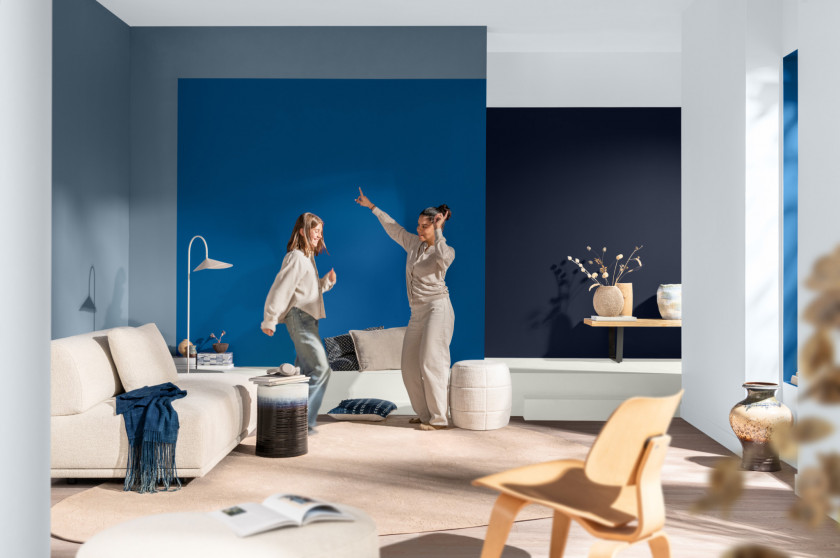 Modern eingerichtetes Wohnzimmer mit den Wandfarben Mellow Flow™ als hellere Wandfarbe und Akzenten im leuchtend blauen Free Groove™ und nachtblauem Slow Swing™