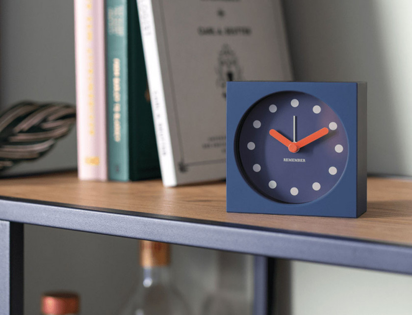 Tischuhr mit Wecker von Remember in der Farbe Midnight mit orangefarbenen Zeigern im Regal